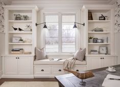 a window seat in front of a white book shelf filled with books and other items