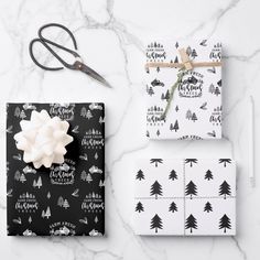 wrapping paper and scissors on a marble countertop with christmas tree designs in black and white