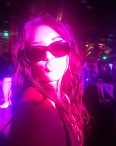 a woman wearing sunglasses and posing for the camera in front of a crowd at a party