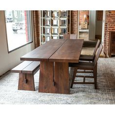 a wooden table with two benches in front of a brick wall and large open window