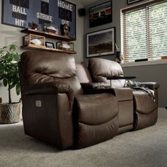 a recliner chair sitting in a living room next to a wall with pictures on it