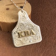 "Here's a variation on the cattle ear tag pendant. This one is also fabricated from a sheet of 18 gauge Sterling silver, with initials or a ranch brand added in an overlay of 22 gauge jeweler's brass. As a variation, the initials or brand can be engraved on a brass disc as shown. The silver is engraved in a traditional Western Bright Cut design for an eye-catching sparkle. Each pendant will vary from what is shown due to the handcrafted process. An inscription on the back is available as an addi Western Silver Engraved Necklaces, Western Style Engraved Silver Necklace, Western Style Silver Engraved Necklace, Personalized Western Silver Jewelry, Personalized Western Style Silver Jewelry, Personalized Silver Western Jewelry, Western Style Engraved Jewelry Gift, Western Style Engraved Sterling Silver Jewelry, Engraved Silver Jewelry For Western-themed Events