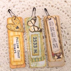 three bookmarks with words and pictures on them sitting on a white carpeted surface