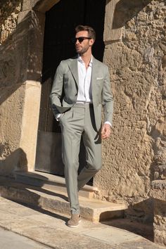 a man in a gray suit and sunglasses walking up steps with his hands in his pockets