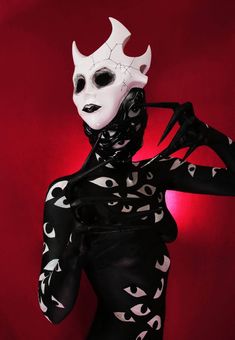 a woman with black and white makeup is wearing a mask