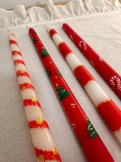 three red and white candles with christmas decorations on them are lined up in a row