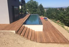 a man laying on top of a wooden deck next to a swimming pool