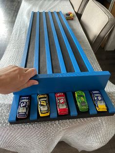 a hand is holding a toy car set in a blue box on top of a table