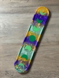 a purple and green skateboard sitting on top of a wooden table with circles painted on it