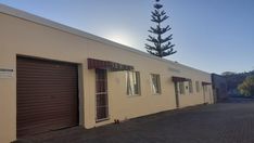 an empty building with two garages next to it and a tree in the background