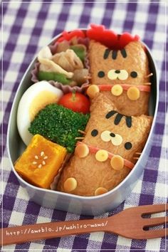 a bento box filled with lots of food on top of a checkered table cloth