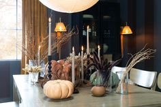 a dining room table with candles and pumpkins