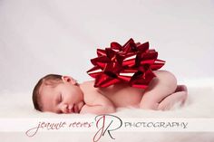 a baby is laying down with a red bow on it's head and body