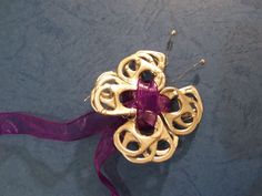 a gold brooch with a purple ribbon around it