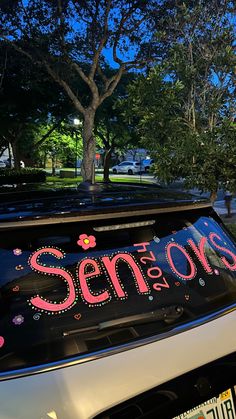 a car with the word seniors written on it's windshield is parked in front of a tree