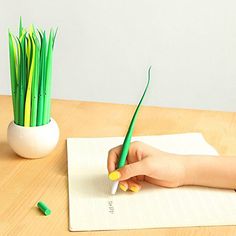 a woman's hand holding a green pen on top of a piece of paper