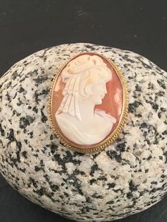 "This is a beautiful vintage 9ct yellow gold cameo brooch. The shell is a dark peach colour with a side view image of a lady in ivory all of which is set in a rope edged 9ct gold casing. There is a small link at the back of the brooch suitable to attach a safety chain if necessary. The brooch/pendant is supplied with a FREE GIFT BOX and I can also gift wrap the brooch if it I sent given as a gift. Dimensions Weight : 7.8g Width : 1\" Length : 1.25\"" Victorian Cameo Brooches In Yellow Gold, Victorian Cameo Brooch In Yellow Gold, Victorian Yellow Gold Cameo Brooches, Oval Cameo Brooches As Gift, Antique Gold Cameo Brooch, Antique Gold Cameo Brooches, Classic Cameo Collectible Brooches, Heirloom Cameo Brooch Gift, Heirloom Cameo Brooches As Gift