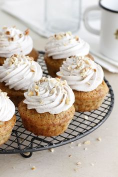 several cupcakes with white frosting on a wire rack