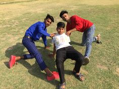 three people are posing for a picture in the grass with one person on his knees