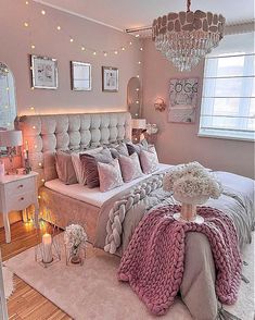 a bedroom decorated in pink and grey with a chandelier hanging from the ceiling