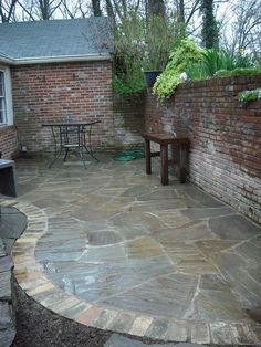 an outdoor patio with flagstone pavers and brick walls