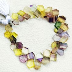 a bracelet made out of multicolored glass beads and a tassel on a white surface