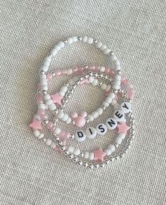 three bracelets with disney letters and pink stars on them sitting on a white surface