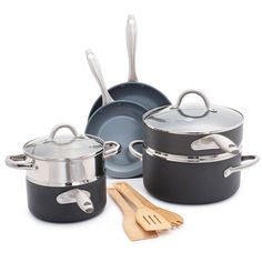 an assortment of pots and pans with wooden utensils next to each other