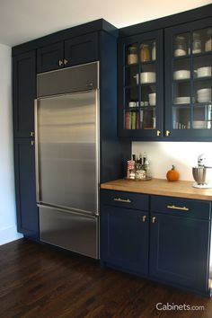 a kitchen with dark blue cabinets and stainless steel refrigerator freezer, wood flooring