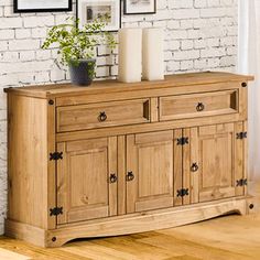 a wooden sideboard with two candles and pictures on the wall