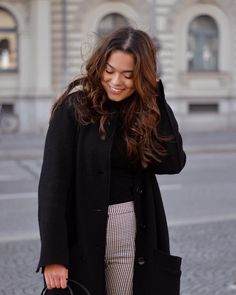 a woman is walking down the street with her hand on her shoulder and holding a purse