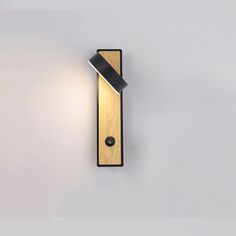 a wall mounted light on the side of a white wall next to a black lamp