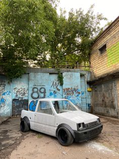 an old white truck parked in front of graffiti covered wall