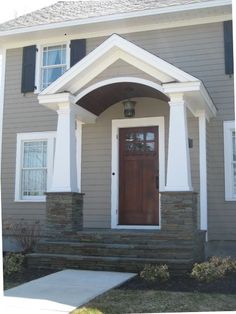 a gray house with white trim and black shutters on the front door is shown