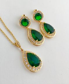 Brilliant & luxurious!! I've created the super sparkly top quality green emerald cubic zirconia teardrop bridal set in gold plated brass setting. The includes : # Earrings featuring a large teardrop with pear cut green emerald cubic zirconia center surrounded by tiny round zirconia crystals. Teardrop dangles from a ear stud with brilliant cut clear cubic zirconia center and surrounded by tiny round zirconia crystals. This entire halo setting gives a brilliantly beautiful effect. Total length Green Sparkling Stones Jewelry Sets For Wedding, Green Cubic Zirconia Jewelry Sets For Weddings, Green Teardrop Jewelry Sets For Anniversary, Green Emerald Jewelry Sets For Wedding, Green Emerald Wedding Jewelry Sets, Green Drop Jewelry For Wedding, Elegant Green Bridal Set For Wedding, Green Cubic Zirconia Teardrop Pendant Jewelry, Emerald Drop Jewelry For Weddings