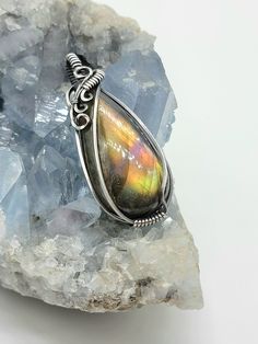 Beautiful flashy labradorite I've had for a while hidden away in my drawer. (There is a video on my Instagram @leetwraps)! Labradorite shows orange, gold, some purple, pink and green. Wrapped in all sterling silver with an asymmetrical type design... This piece will come on a 20 inch stainless steel chain as seen in photos and in a gift box! Iridescent Sterling Silver Spiritual Jewelry, Iridescent Gemstone Jewelry With Spiritual Style, Unique Iridescent Jewelry With Natural Stones, Iridescent Gemstone Jewelry For Spiritual Style, Artisan Iridescent Gemstone Jewelry, Handmade Iridescent Jewelry For Collectors, Spiritual Iridescent Gemstone Jewelry, Handmade Iridescent Collectible Jewelry, Iridescent Unique Jewelry