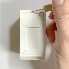 a person is painting the inside of a white cabinet with a paint roller and brush