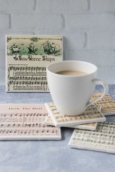 a cup of coffee sitting on top of a table next to sheet music and a sign