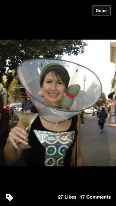 a woman wearing a hat and holding a martini in her hand while standing on the street