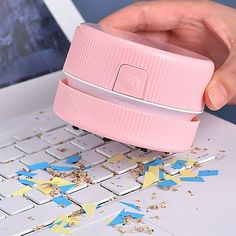 a person is using a pink plastic device to remove confetti from their laptop