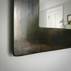 there is a mirror on the wall in this room that looks like it has been made out of metal