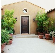 a house with potted plants in front of it and a door on the side