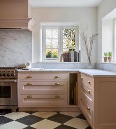 a kitchen with checkered flooring and pink cabinetry is pictured in this image