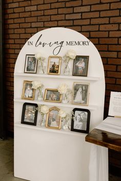 an arch with pictures and flowers on it for a wedding memory display in front of a brick wall