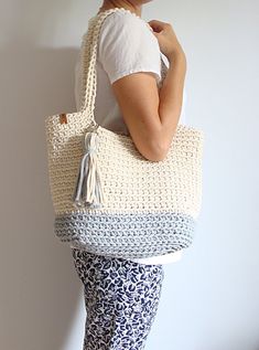 a woman is holding a crocheted bag