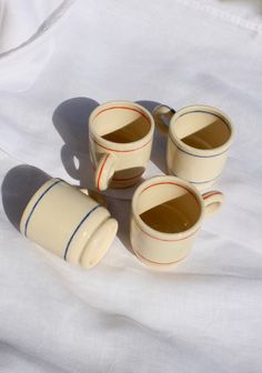 four coffee cups sitting on top of a white sheet