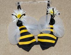 two yellow and black bee shaped hair clips with white flowers on each side of the ears