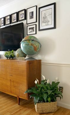 a living room with a television, potted plant and pictures on the wall