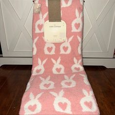 a pink and white blanket on top of a wooden floor in front of a door