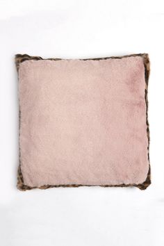 a pink and brown pillow sitting on top of a white table next to a vase